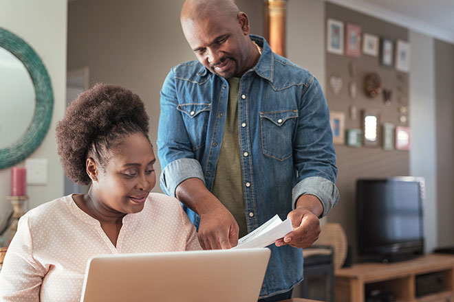 Couple Reviewing Papers In Front of a Computer